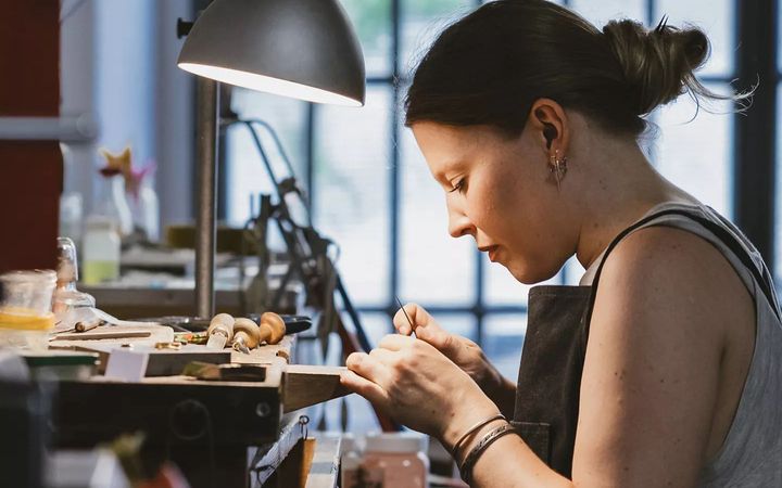 An artisan at a jeweler’s bench working on a custom diamond engagement ring