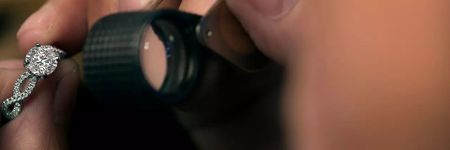 white male hands holding diamond ring and jeweler's loupe