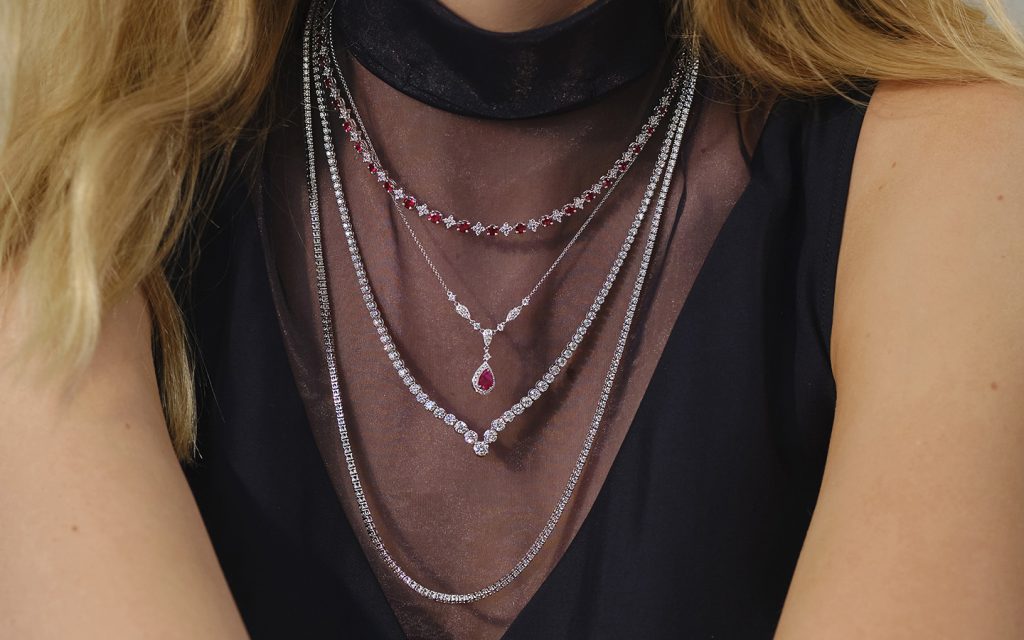 Close up of woman’s necklace stack, she is wearing ruby and diamond jewelry.