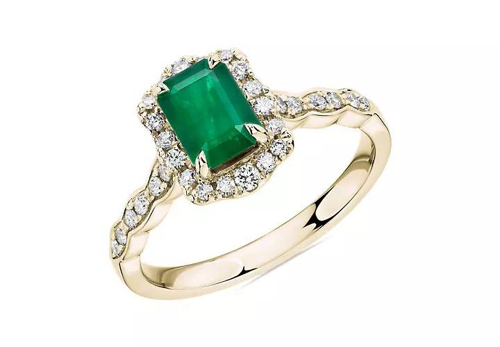 An emerald engagement ring ornamented by diamonds and gold filigree