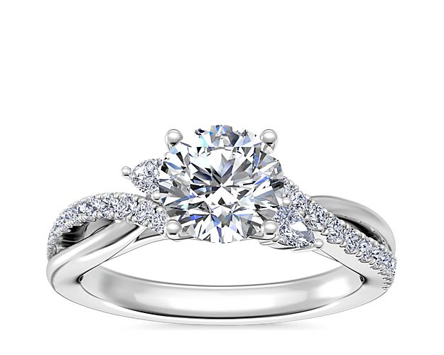 Mesmerize your love with this brilliant engagement ring featuring a center stone accentuated by petal-inspired accent diamonds. The elegant platinum design features twisting split shank, with one arm of each shank inlaid with shimmering pavé-set diamonds.