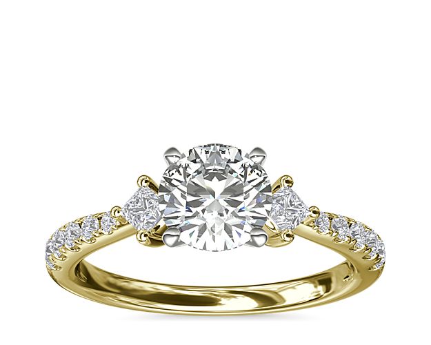 Romantic style meets classic beauty. This unforgettable design features two east-west princess-cut diamond sidestones and 10 round pavé-set diamonds flanking the center stone of your choice set in 14k yellow gold.