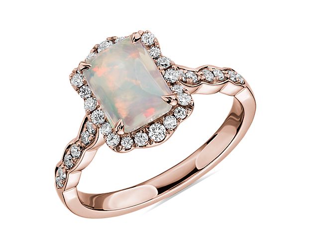 This beautiful emerald cut opal is paired with 14k rose gold and encased in a diamond halo for a unique and romantic look.