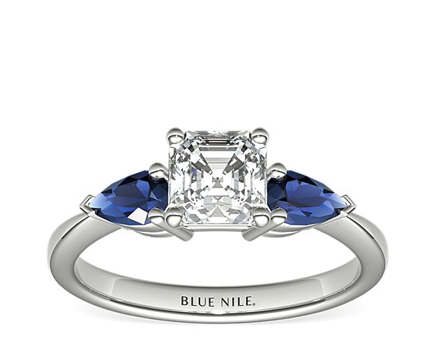 Two velvety medium dark blue pear-shaped sapphires, set in elegant 18k white gold, draw the eye directly to the center diamond of your choice, making it the star of the show.