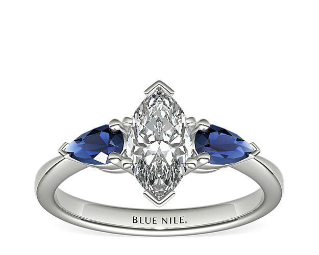 Two velvety medium dark blue pear-shaped sapphires, set in elegant platinum, draw the eye directly to the center diamond of your choice, making it the star of the show.