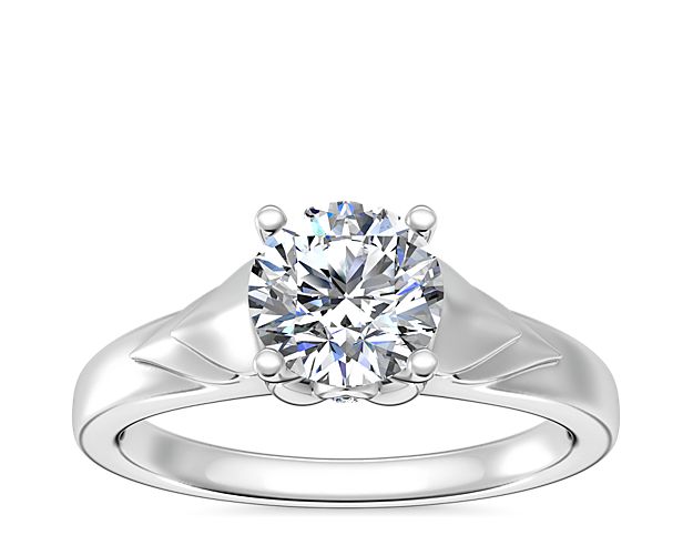 Love shines brilliantly in this solitaire engagement ring featuring a unique chevron design in gleaming 18k white gold. A hidden accent diamond shimmers at the side, adding elegance.