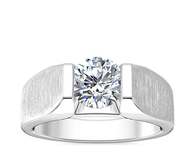 A shimmering tension-style diamond setting adds beautiful sparkle to this handsome men's engagement ring. The polished 18k white gold promises a luxurious gleam and timeless quality.