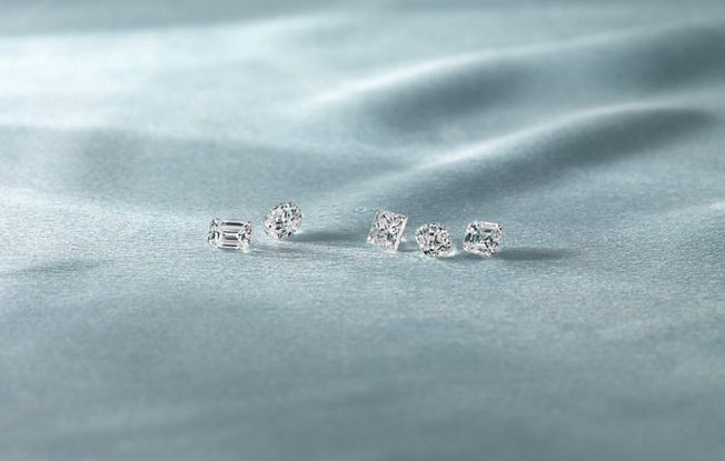 5 loose diamonds of various cuts on a blue background