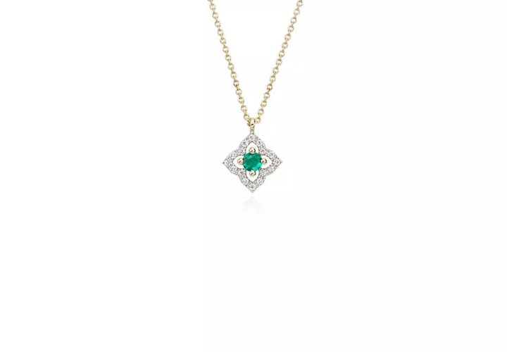 A floral, vintage-inspired May birthstone pendant with round emerald center framed in diamond micropavé petals set in yellow gold and suspended from matching cable chain